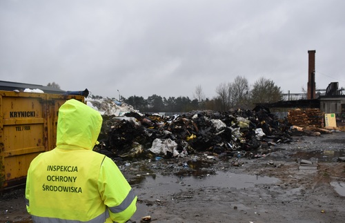 Inspektor Wojewódzkiego Inspektoratu Ochrony Środowiska prowadzi oględziny miejsca pożaru odpadów.