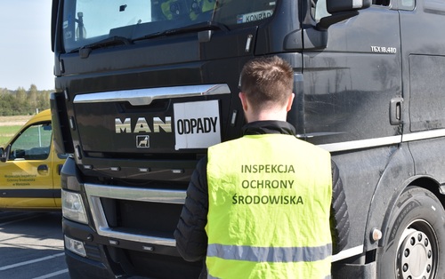 Inspektor Wojewódzkiego Inspektoratu Ochrony Środowiska w Warszawie prowadzi kontrolę samochodu ciężarowego.