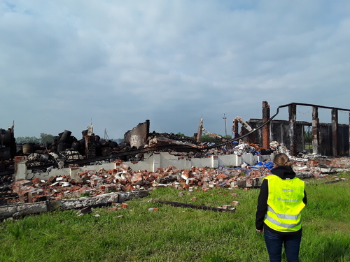 Inspektor Wojewódzkiego Inspektoratu Ochrony Środowiska w Warszawie kontroluje pogorzelisko po spalonym budynku magazynowym.