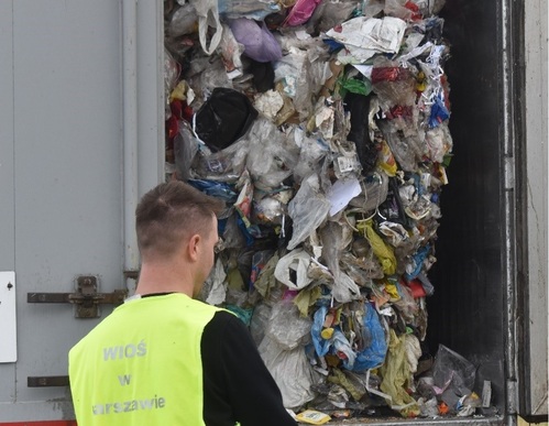 Inspektor Wojewódzkiego Inspektoratu Ochrony Środowiska w Warszawie kontroluje odpady przewożone na naczepie samochodu ciężarowego.