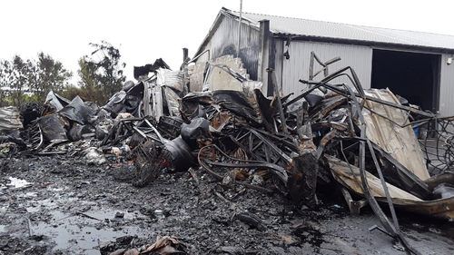 Pogorzelisko po pożarze wiaty magazynowej oraz znajdujące się obok spalone odpady.